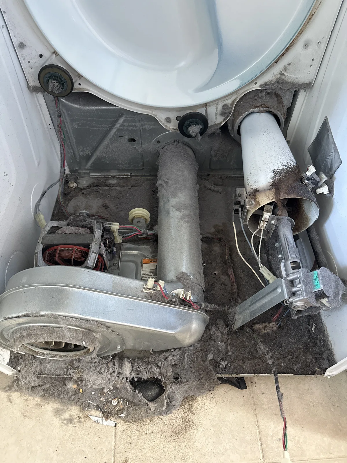Lint coating the base and components inside an opened dryer during service